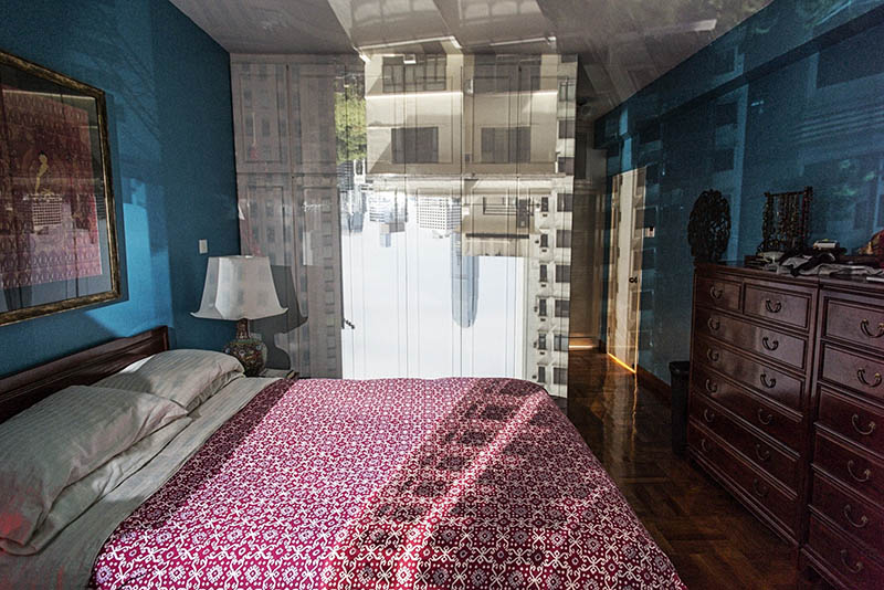 Color Photograph of Bedroom with Cityscape Projected On It.
